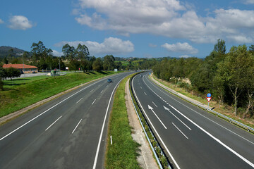 open curve on the A8 Cantabrian highway with three lanes in each direction seen from the pedestrian...