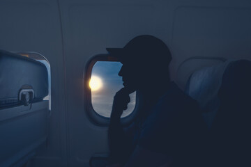 A pensive man sits at the window on an airplane.
