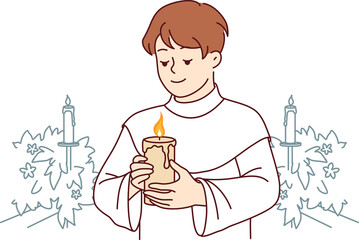 Boy participates in holy communion and holds burning candle for christian religious ritual in church