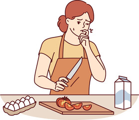Woman housewife cooking dinner cut finger and is trying to stop bleeding, standing in kitchen