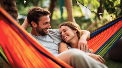 Happy young traveling couple resting together on a hammock during camping in nature - obrazy, fototapety, plakaty