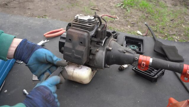 remove the muffler brush cutter,a man repairs a brush cutter by disassembling it for parts