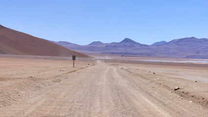 Fototapeta na wymiar Bolivia, Salvador Dali Desert. Avoroa Nationa Park, A road leading through the desert towards the mountains.