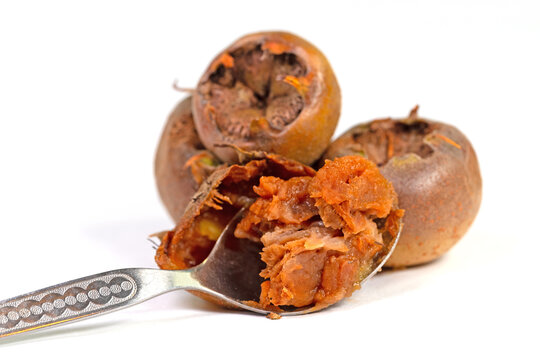 Mispeln und Fruchtfleisch auf einem L&ouml;ffel vor wei&szlig;em Hintergrund
