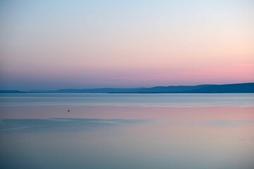 Aerial view of a beautiful sunset in the sea with a boat and a pink sky in the background