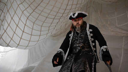 Pirate captain in an embroidered doublet and cocked hat with an antique pistol in his hand,...
