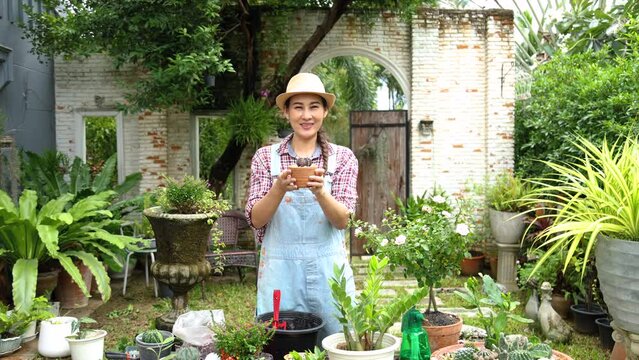 Asian cheerful gardening woman working planting flower tree in backyard on weekend, freelance worker earn income growing plants in small business garden shop owner, gardener happy with new occupation