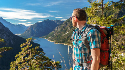 Ein Wanderer blickt auf den Plansee in Österreich hinab. Der Stausee in den Alpen sieht aus wie ein norwegischer Fjord.