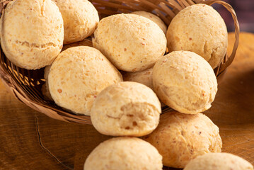 Cheese bread, basket with cheese bread arranged on rustic wood, dark background, selective focus.