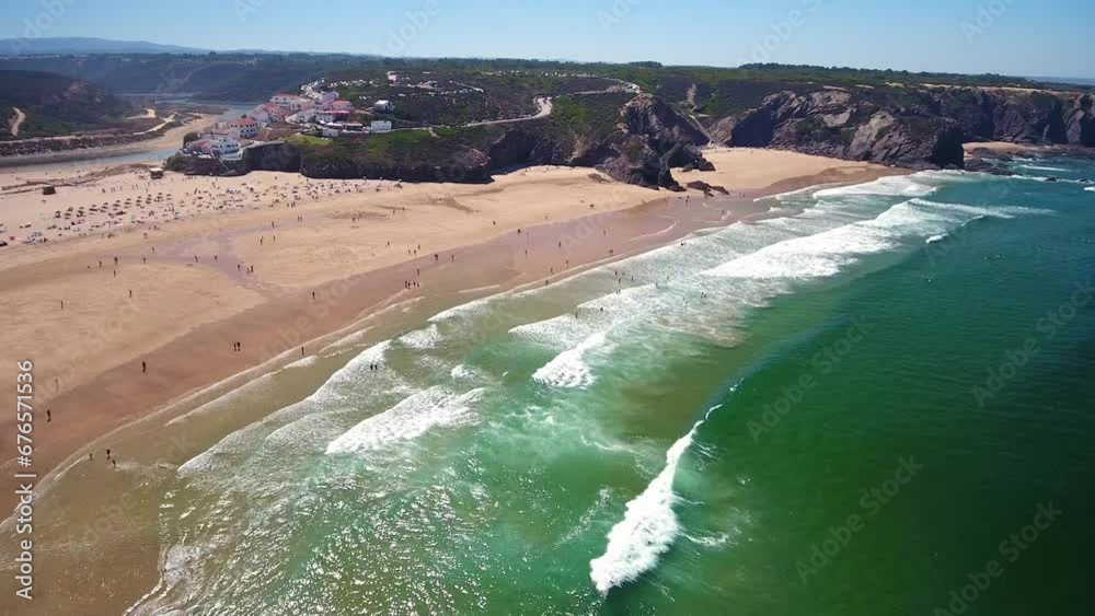 Canvas Prints Aerial video filming by drone of the sea bay and beach near the village of Odeceixe Alentejo Portugal. Beach with tourists in the background and surfers in the water.