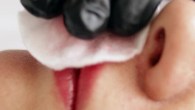 Permanent makeup procedure applying rose red pigment using tattoo machine in beautician salon. Microblading tattoo lips, close up	
