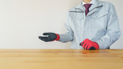 手で案内する作業服にネクタイの男性