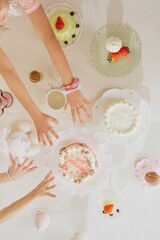 Birthday white cake with human hands and other cookies on table