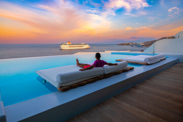 Man relaxes on the sunbed during sunset time at Mykonos, Greece