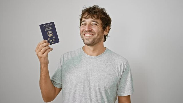 Young man bursting with joy holds up his passport to hong kong, exuding confidence and happiness against a pristine white background
