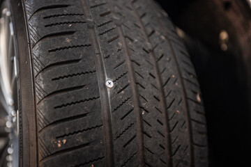 A screw stuck in a car tire puncturing it and making it flat