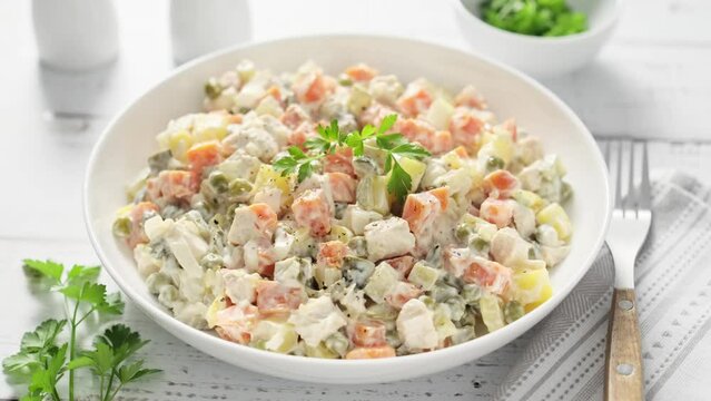 Olivier salad, russian creamy salad with boiled potato and carrot, chicken meat, pickled cucumber, green pea, onion and mayonnaise. Stock footage video 4k