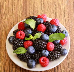 Raspberries, blackberries and blueberries in white bowl.