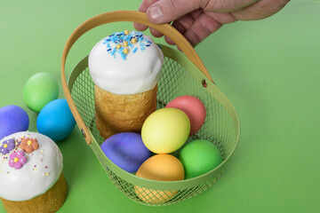 Easter cake and easter eggs in a basket on green background