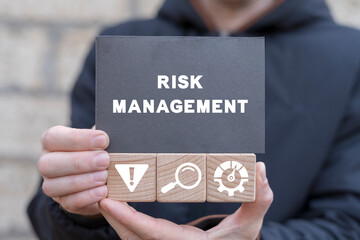 Manager holding wooden cubes with icons and black  sticky note with text: RISK MANAGEMENT. Effective risk management, analyze potential danger level, measurement, monitoring, assessment and control.