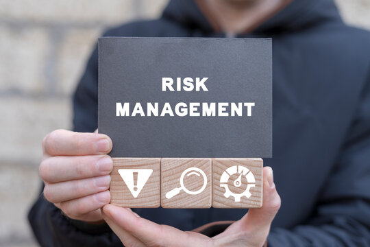 Manager holding wooden cubes with icons and black  sticky note with text: RISK MANAGEMENT. Effective risk management, analyze potential danger level, measurement, monitoring, assessment and control.