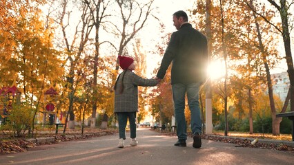 Loving father takes leisurely stroll through public garden with adorable daughter