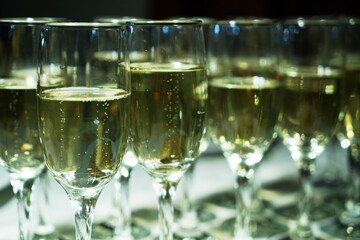 a stylishly set table with a glass of champagne. A charming glass filled with sparkling drink shines in the light. The table is covered with an elegant tablecloth