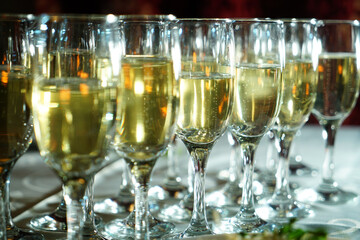 a stylishly set table with a glass of champagne. A charming glass filled with sparkling drink shines in the light. The table is covered with an elegant tablecloth