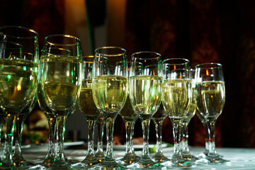 a stylishly set table with a glass of champagne. A charming glass filled with sparkling drink shines in the light. The table is covered with an elegant tablecloth