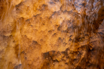 Long Exposure Of Rushing Water Over Orange Rock