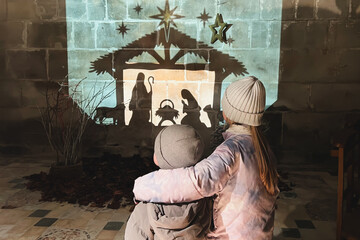 Children look at christmas creche with Joseph Mary and small Jesus in a crib