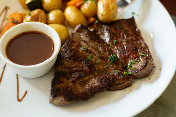 Dish in old bistro in Limoges, France, Limousin cattle beef steak served with oven baked potatos, vegetables and served with light broth or gravy