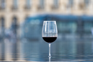 Tasting of Bordeaux blended red wine with wine city Bordeaux on background, left bank of Gironde Estuary, France. Glass of red French wine.