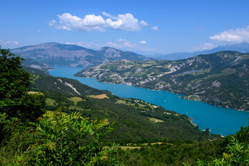 Fototapeta na wymiar Aerial view on blue Lake of Serre-Poncon, reservoir border between Hautes-Alpes and Alpes-de-Haute Provence  departments, one of largest in Western Europe