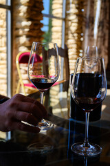 Tasting of red dry wine in Chateauneuf-du-Pape wine making village in France with green vineyards on large pebbles galets and sandstone clay soil