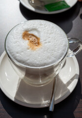 Drinking tasty fresh brewed Italian caffe latte coffee with whipped milk in outdoor cafe