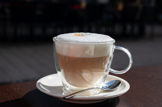 Drinking tasty fresh brewed Italian caffe latte coffee with whipped milk in outdoor cafe