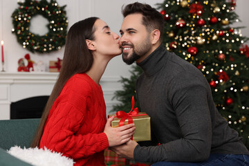 Beautiful young woman thanking her boyfriend for Christmas gift at home