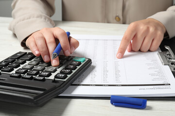 Woman making calculations on calculator at table, closeup