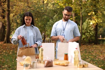 Volunteers packing food products at table in park