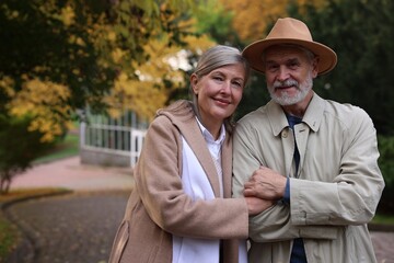 Portrait of affectionate senior couple in autumn park, space for text