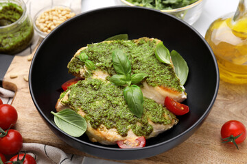 Delicious chicken breasts with pesto sauce, tomatoes and basil on table, closeup