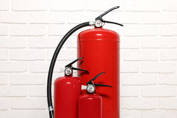 Red fire extinguishers near white brick wall