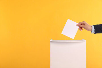 Woman putting her vote into ballot box on orange background, closeup. Space for text