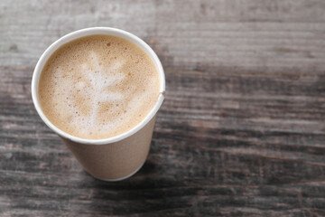 Coffee to go. Paper cup with tasty drink on wooden table, closeup. Space for text