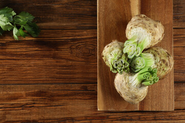 Fresh raw celery roots on wooden table, top view. Space for text