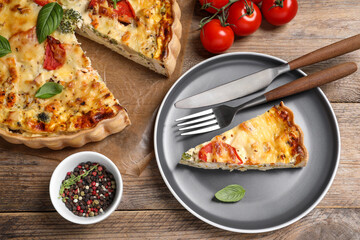 Tasty quiche with tomatoes, basil and cheese served on wooden table, flat lay