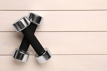 Metal dumbbells on white wooden table, flat lay. Space for text