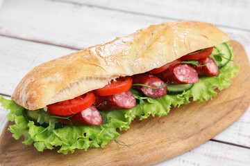 Delicious sandwich with sausages and vegetables on white table, closeup