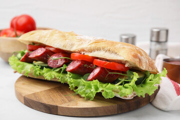 Delicious sandwich with sausages and vegetables on white table, closeup